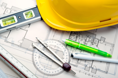 Hard hat sitting on top of architectural drawings, with pens, a level, and a protractor