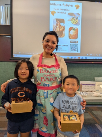 A woman with 2 children who are holding cupcakes.