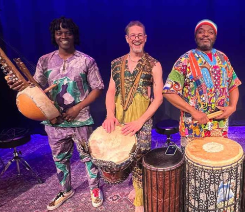 Three percussionists standing in a row with African drums