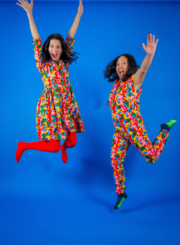 A photo of 2 women jumping with their arms up.