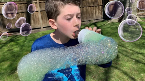 Boy blowing bubbles that look like a snake