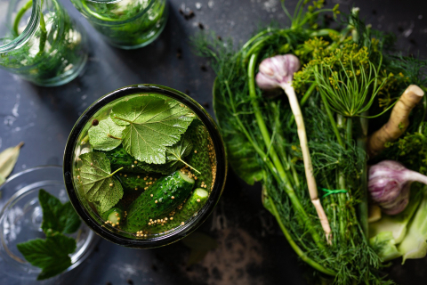 A photo of a jar filled with fresh herbs, and fresh herbs next to the jar as well.
