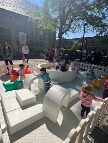 Photo of kids playing on small, white, playground equipment outdoors.