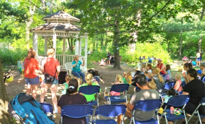 Photo of a group of people, seated outdoors listening to a storytime.