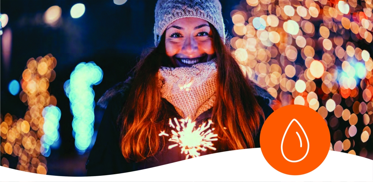 Woman holding sparkler with xmas lights in background