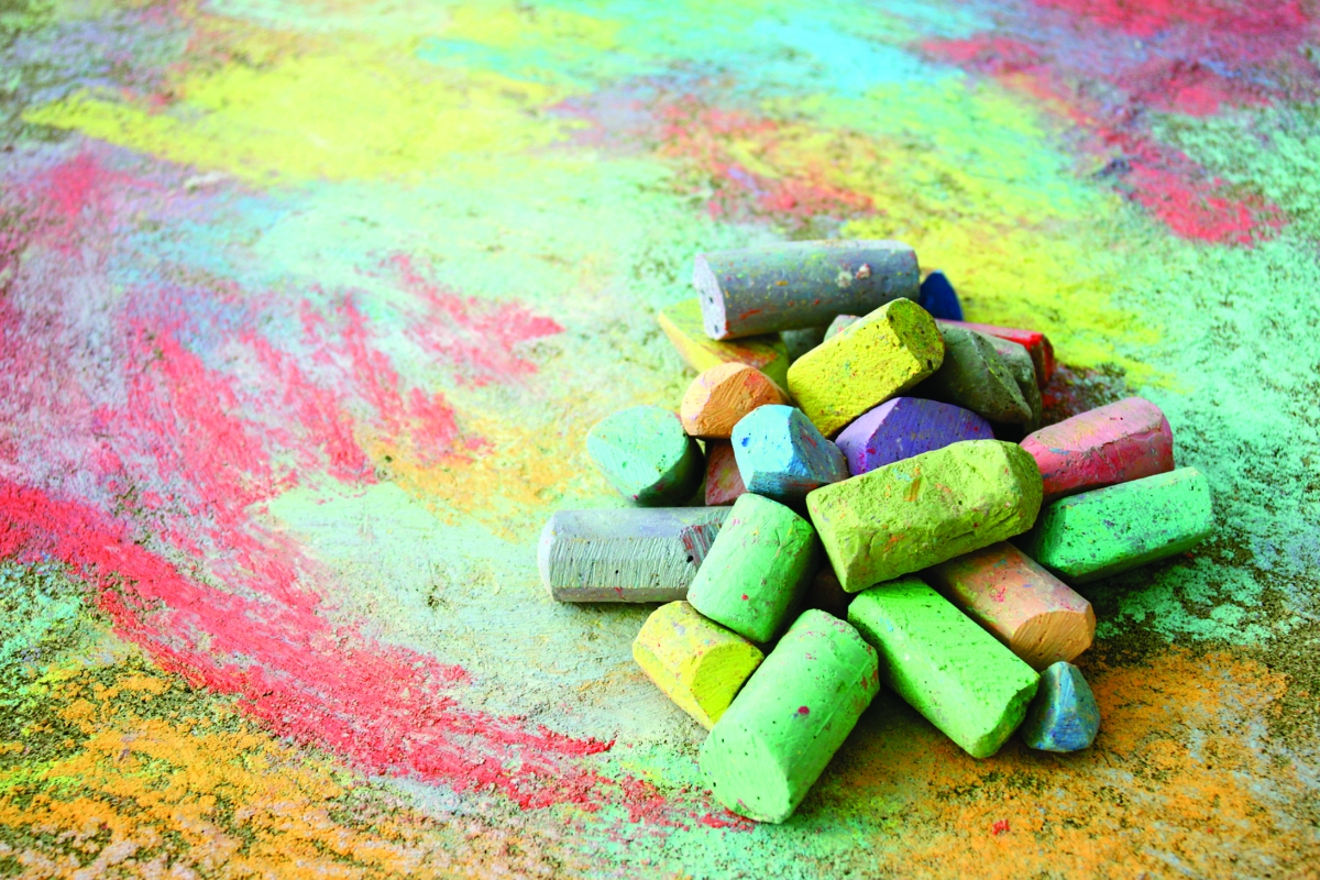 Various pieces of colored chalk on chalk covered sidewalk