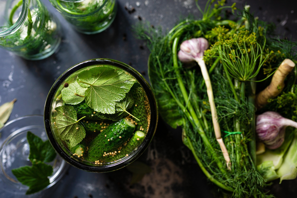 A photo of a jar filled with fresh herbs, and fresh herbs next to the jar as well.