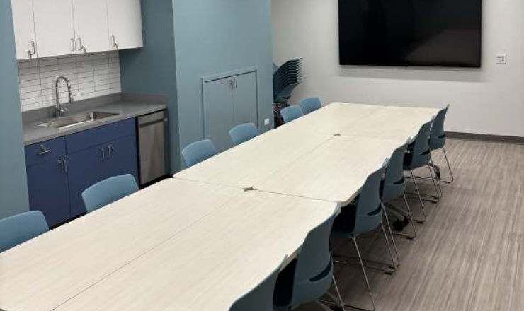 Meeting room with long conference table and chairs, screen and sink